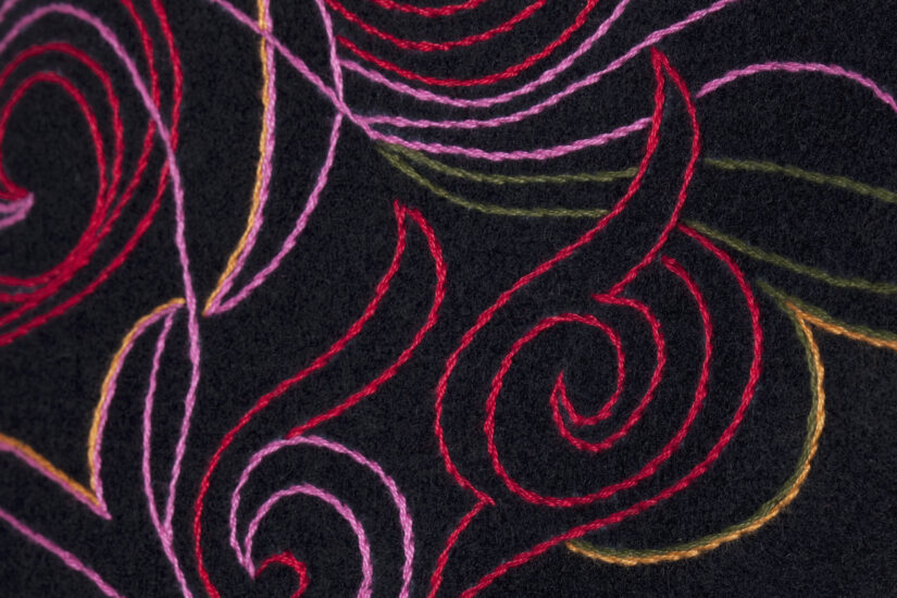 Detaljer av stort brodert jakkemønster i rosalill farger